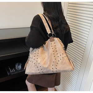 Vue arrière d'un mannequin portant un sac à bandoulière beige à rivets et anneaux