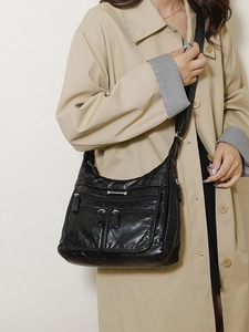 Classic black soft leather crossbody bag with multiple zippers and wide strap on model