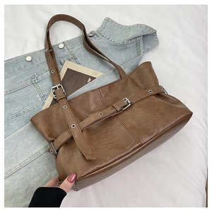 Dettaglio borsa tote marrone vintage con fibbie argentate e decorazioni con occhielli