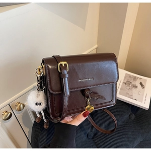 Détail du sac vintage marron foncé en simili cuir avec breloque peluche et bijou doré