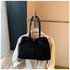 Détail du sac fourre-tout en daim noir avec ferrures dorées et breloque en cuir