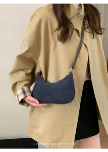 Dettaglio borsa hobo in pelle scamosciata blu scuro con tracolla marrone e trench