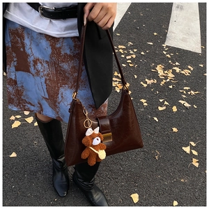 Gros plan d'un sac à bandoulière vintage en cuir verni marron avec un ourson mignon
