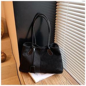 Vue détaillée du sac cabas noir en daim avec anses en cuir et breloque décorative sur le côté