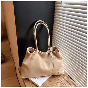 Détail du grand sac cabas en daim abricot sur une table en bois sous lumière douce