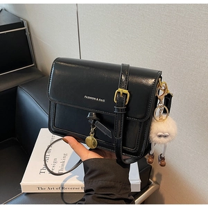 Vue détaillée du sac carré en cuir noir brillant avec logo blanc et charm monstre mignon