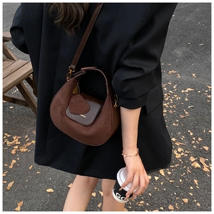 Detail shot of vintage dark brown suede and leather crossbody bag with heart charm