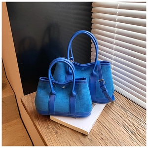 Minimalist blue suede bucket bags in large and small sizes with leather handles and straps