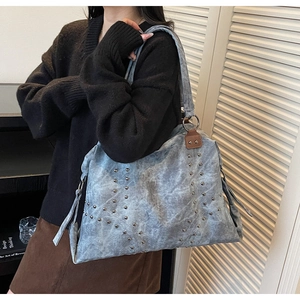 Détail du sac cabas en toile bleue avec clous argentés et patchs en cuir marron