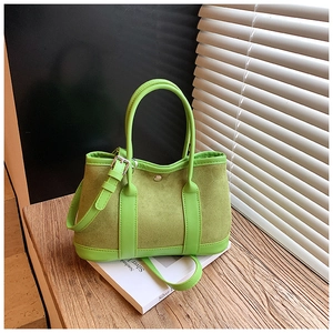 Detail of green suede and leather bucket bag featuring metal magnetic buckle on books
