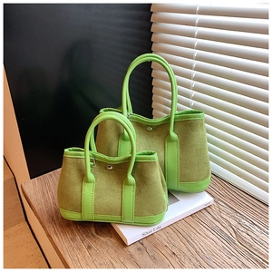 Detail view of green suede tote bag set with light green leather handles and metal button