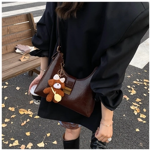 Détail du cuir huilé marron foncé du sac hobo rétro avec un pendentif ours en peluche