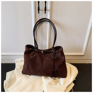 Détail du sac cabas en daim marron foncé avec poignées en cuir brillant et texture riche