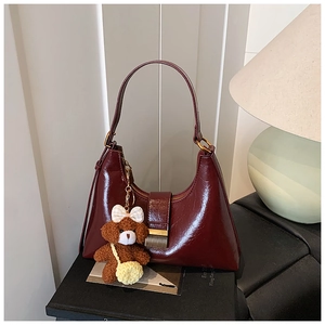 Détail du sac demi-lune bordeaux avec finition brillante et breloque en peluche pour sac