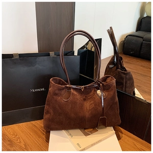 Détail d'un sac cabas rétro en daim marron reflété dans un miroir au ton chaleureux