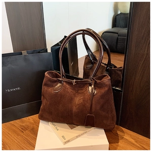 Détail d'un sac cabas en daim marron vintage avec lanières en cuir et coutures verticales
