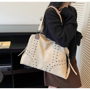 Détail d'un grand sac cabas avec des clous argentés et des bretelles en cuir
