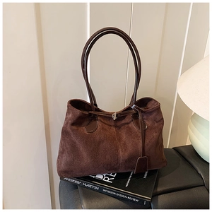 Détail du sac cabas en daim marron foncé avec fines bretelles et texture rétro chic