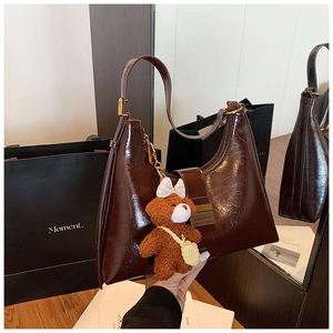 Gros plan détaillé d'un sac croissant marron foncé avec boucle dorée et charm ours