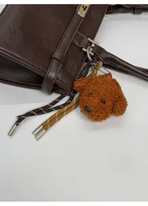 Close-up of a plush dog bag charm on a dark brown leather handbag with braided details