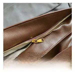 Close-up of premium brown lychee textured leather bag with gold zipper and gray lining