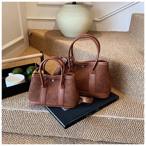 Close-up of tan suede bucket bag set featuring two sizes on artistic lifestyle background