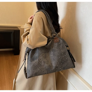 Détails d'un grand sac cabas gris avec rivets métalliques et finitions en cuir brun