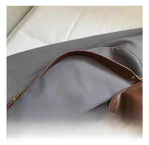 Close-up of brown litchi grain leather bag featuring wide strap and golden metal hardware
