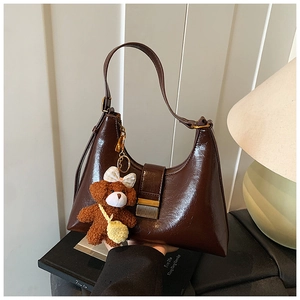 Détail du sac hobo en cuir verni marron foncé avec charmant petit ours en peluche