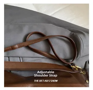 Close-up of litchi pattern leather strap and adjustable metal buckle on tote bag