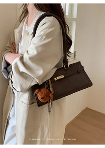 Detail view of a vintage dark brown shoulder bag with a cute plush bear charm