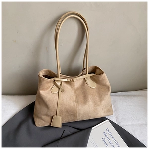 Gros plan sur un sac cabas en daim beige avec sangle en cuir et détail de l'étiquette