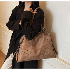Gros plan sur un sac cabas clouté rétro avec texture vintage et cordon de serrage latéral
