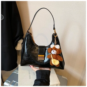 Détail du sac hobo en cuir verni brillant noir avec fermeture éclair dorée et ours