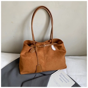 Détail d'un sac cabas en daim marron avec boucle en métal sur une veste grise