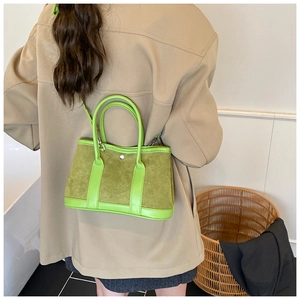 Detail of green suede and leather patchwork tote bag with silver buckle and crossbody strap