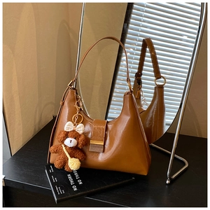 Détail d'un sac à bandoulière marron avec un ourson décoratif et boucle en métal