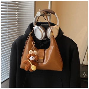 Détail du sac rétro caramel avec charm ours sur un sweat à capuche noir décontracté
