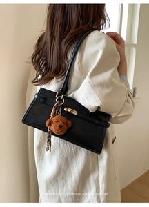 Detail of vintage matte black shoulder bag with gold hardware and teddy bear charm