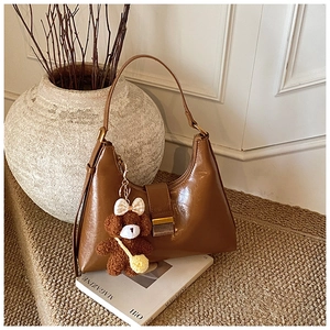 Détail d'un sac hobo vintage marron avec texture en cuir brillant et breloque ours peluche