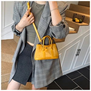Detailed view of yellow mini bucket bag with mixed textures and adjustable crossbody strap