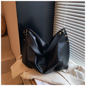 Close-up of black lychee-grain leather tote bag with stylish metal rivet hardware details