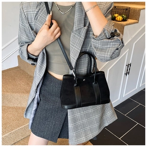 Detail of black matte and smooth leather bucket bag with top handles and shoulder strap