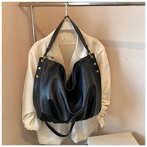 Detail of matte black soft leather tote bag with gold rivets and thick shoulder straps