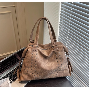 Vue détaillée d'un grand sac cabas vintage marron avec des rivets et une surface texturée
