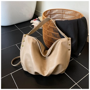 Detail of beige faux leather hobo bag featuring gold rivets and versatile dual straps
