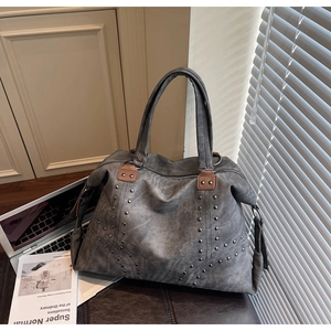 Détail d'un grand sac cabas gris avec rivets argentés et texture cuir vintage pour le travail