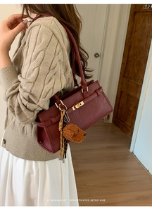 Detail of retro burgundy bucket bag with vintage gold turn-lock and dog charm