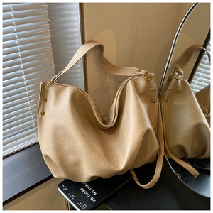 Close-up of beige soft leather hobo bag with gold rivet accents and metal ring details