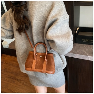 Detail showing the brown suede crossbody bucket bag with elegant silver twist lock closure